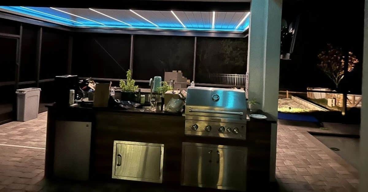 Solid roof pergola covering an outdoor kitchen with LED lighting