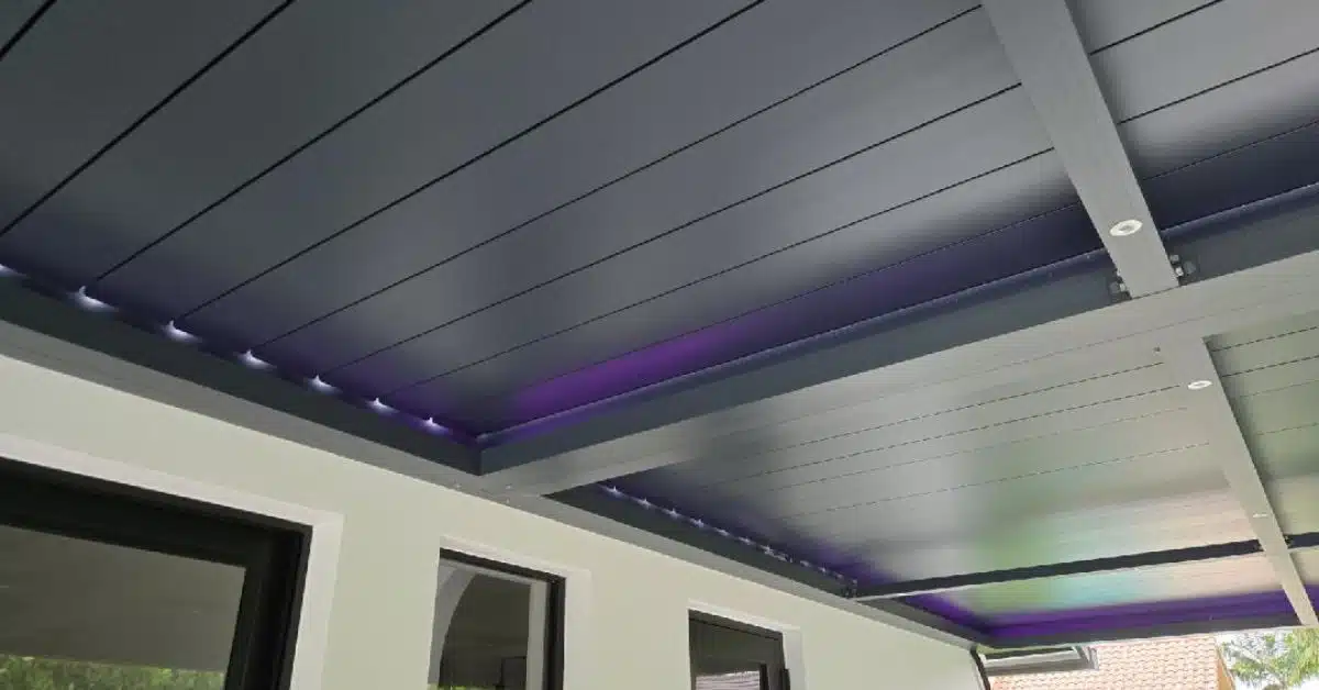 Custom RGB and Task Lighting for Modern Pergolas - enVision Pergola A close-up of a dark grey pergola ceiling featuring a combination of purple RGB perimeter lighting and white recessed lights in the support beams.