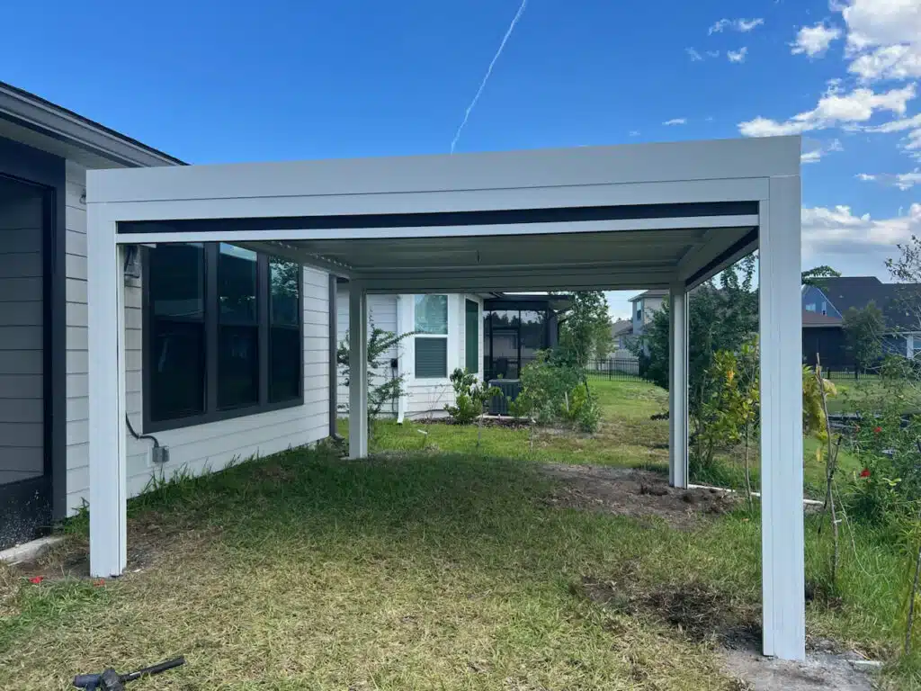 White open-sided patio cover attached to the house, over a grassy backyard.