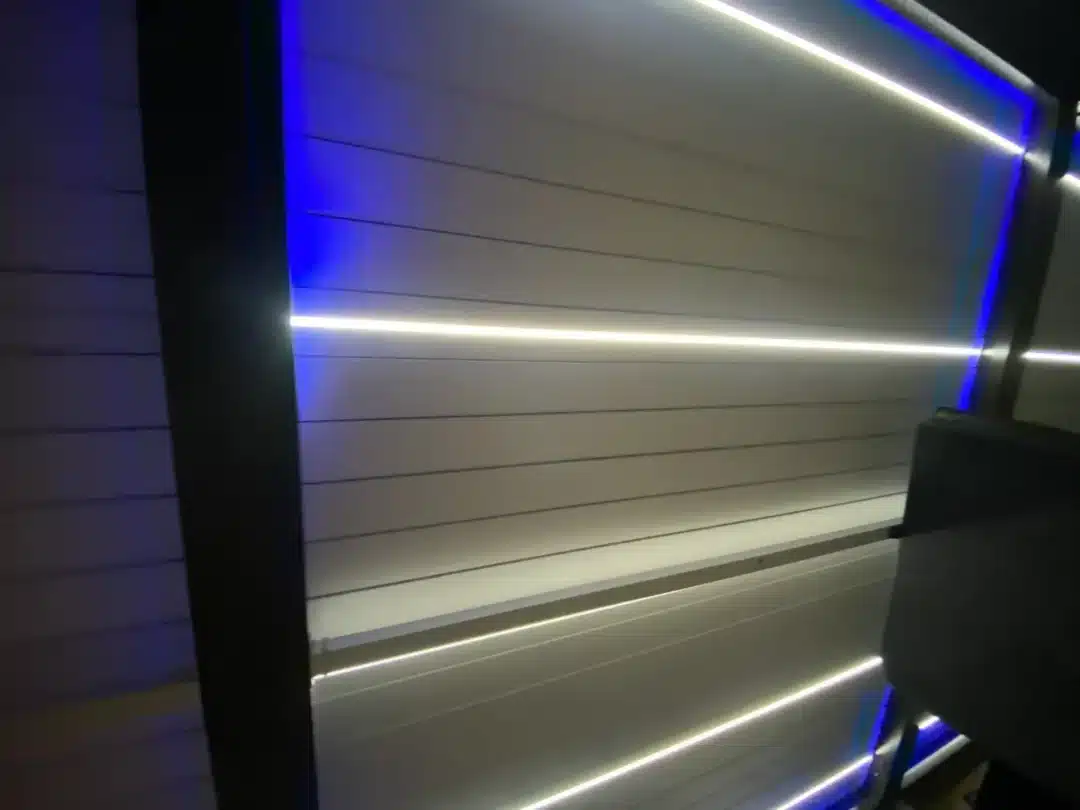 Interior of a modern elevator with brushed metal slat walls and blue/white LED strips at the edges.